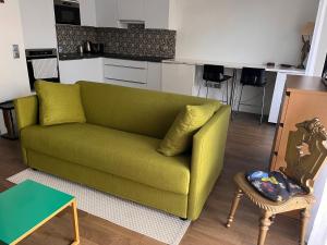 un sofá verde en una sala de estar con cocina en Apartment close to Paris and métro en Le Pré-Saint-Gervais