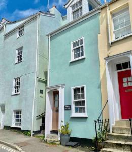 a blue house with a red door on a street at High end cottage in amazing location. Only 1 minute from the sea! Beautifully decorated 3 level home. 5* reviews in Lyme Regis