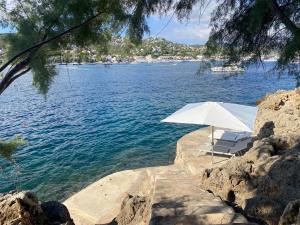 ein weißer Regenschirm und Stühle neben dem Wasser in der Unterkunft Villa La Mola in Andratx