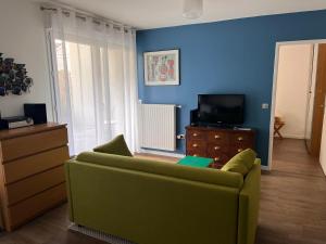 een woonkamer met een groene bank en een tv bij Apartment close to Paris and métro in Pré Saint Gervais