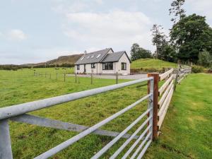 a white house in a field with a fence at Creag-na-Sanais in Laggan