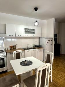 - une cuisine blanche avec une table et des chaises blanches dans l'établissement Apartman Sunce, à Požarevac