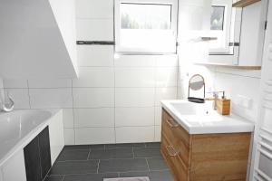 biała łazienka z umywalką i lustrem w obiekcie Appartement Mauterndorf w mieście Mauterndorf