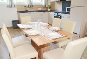 kuchnia z drewnianym stołem i białymi krzesłami w obiekcie Appartement Mauterndorf w mieście Mauterndorf