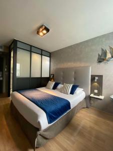 a large bedroom with a large bed with blue sheets at Hotel Best Western La Mare Ô Poissons in Ouistreham