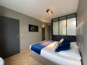 a bedroom with a large bed with blue pillows at Hotel Best Western La Mare Ô Poissons in Ouistreham