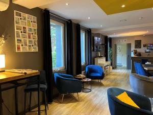 a living room with blue chairs and a table at Hotel Best Western La Mare Ô Poissons in Ouistreham