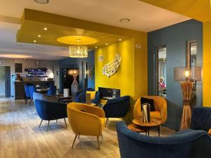 a lobby with blue chairs and a yellow wall at Hotel Best Western La Mare Ô Poissons in Ouistreham