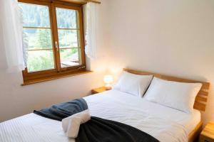 Schlafzimmer mit einem weißen Bett und einem Fenster in der Unterkunft Peacefull Mountains View in Kandersteg