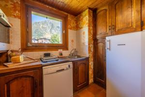 une cuisine avec un réfrigérateur blanc et une fenêtre dans l'établissement Chalet Corzelet ski in - ski out - Happy Rentals, à Chamonix-Mont-Blanc