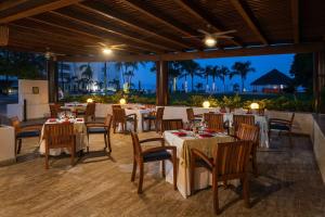 restauracja ze stołami i krzesłami z widokiem na ocean w obiekcie Wyndham Alltra Vallarta, All-Inclusive Resort w mieście Nuevo Vallarta