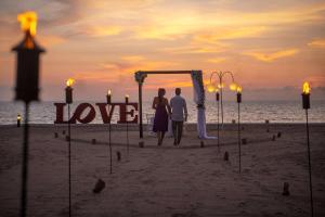 a couple standing under a love sign on the beach at Wyndham Alltra Vallarta, All-Inclusive Resort in Nuevo Vallarta 