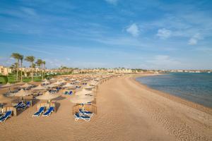 a beach with chairs and umbrellas and the ocean at Cleopatra Luxury Resort Makadi Bay in Hurghada