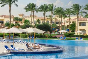 einen Pool in einem Resort mit Liegen und Sonnenschirmen in der Unterkunft Cleopatra Luxury Resort Makadi Bay in Hurghada