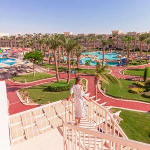 a woman standing on a balcony looking at a park at Pickalbatros Palace - Aqua Park Hurghada in Hurghada