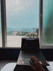 a person sitting on a bed with a laptop at Joey's By The Ganges in Rishīkesh