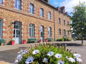 ein Backsteingebäude mit Bänken und Blumen davor in der Unterkunft La Récréation in Châtelaudren