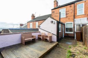 a wooden deck with two benches and a building at Cosy home in City Centre in Lincolnshire