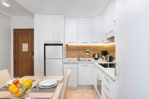 a kitchen with white cabinets and a table with a bowl of fruit at Royal Sunset Beach Club in Adeje