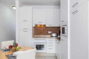 a kitchen with white cabinets and a wooden table at Royal Sunset Beach Club in Adeje