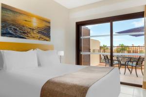 a bedroom with a bed and a balcony with a table at Royal Sunset Beach Club in Adeje