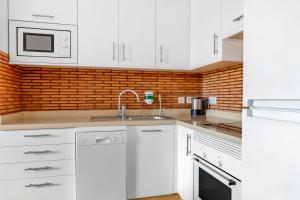 a kitchen with white cabinets and a brick wall at Royal Sunset Beach Club in Adeje