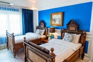 two beds in a bedroom with blue walls at The White Rabbit Hostel in Ban Si Than
