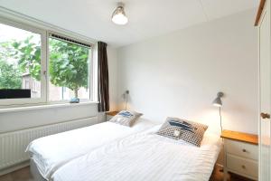 a bedroom with a white bed and a window at Boathouse Suburban Amsterdam in Uitgeest