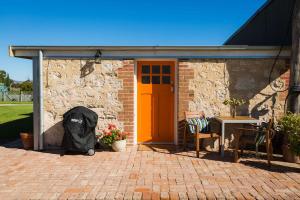 una casa de ladrillo con puerta de color naranja, mesa y sillas en Orange Door Bnb en Currency Creek