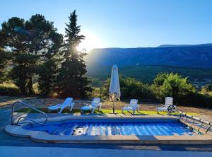 a swimming pool with chairs and an umbrella at Casa El Rincón del Guardal in Huéscar