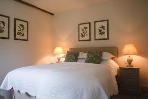 a bedroom with a white bed with two lamps at Cowdray Holiday Cottages in Midhurst