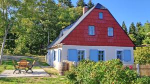 una casa roja y blanca con un banco delante en Ferienhaus FERGUNNA en Marienberg