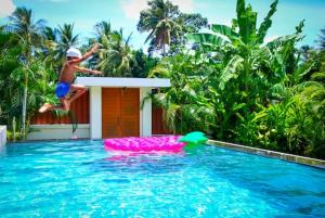un jeune garçon sautant dans une piscine dans l'établissement -20 Off per cent Luxury Mango Villa, à Bophut 