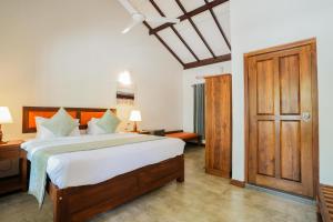 sypialnia z dużym łóżkiem i drewnianymi drzwiami w obiekcie Malala Retreat w mieście Hambantota