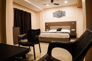 1 dormitorio con cama, sillas y mesa en Hotel De L'amour, en Port Blair