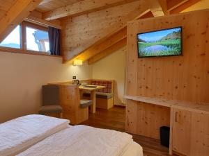 a bedroom with a bed and a tv on the wall at DOLOMITES B&B - Suites, Apartments and SPA in Tesero