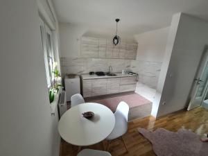 Apartman CRYSTAL في برتشكو: مطبخ أبيض مع طاولة بيضاء وكراسي بيضاء