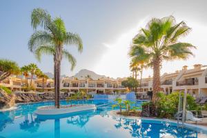 a pool at the resort with palm trees and buildings at Royal Sunset Beach Club in Adeje