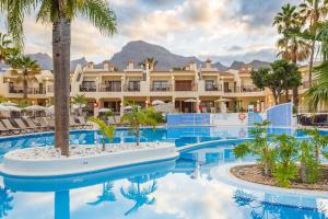 a resort with a pool with palm trees and a building at Royal Sunset Beach Club in Adeje