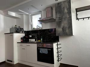 a kitchen with white cabinets and a black stove at Dominik in Dernbach