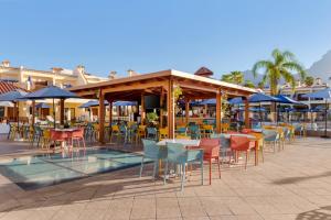 een patio met tafels, stoelen en parasols bij Royal Sunset Beach Club in Adeje