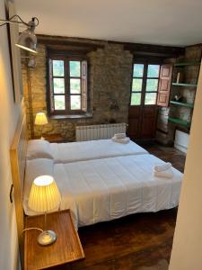 1 dormitorio con 1 cama y 1 mesa con lámpara en Casa Rural Basiver - Habitación Pico San Carlos en Armaño