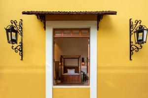un mur jaune avec une fenêtre et des lumières sur celle-ci dans l'établissement Hacienda Xcanatun, Angsana Heritage Collection, à Mérida