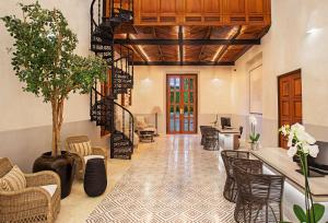 a lobby with a staircase and chairs and a tree at Hacienda Xcanatun, Angsana Heritage Collection in Mérida