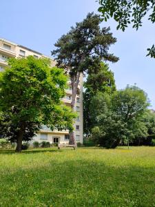 ein Gebäude mit einem Baum in der Mitte eines Feldes in der Unterkunft L'Edelweiss Campus & Parking privé securisé in Gières