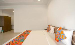 a bedroom with a large white bed with colorful pillows at FabHotel Yamunotri Retreat, Tapovan in Rishīkesh