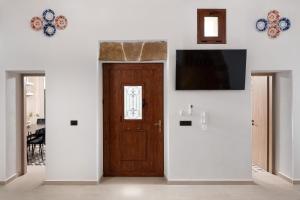 a room with a wooden door and a television on a wall at Antica Casa Dei Nonni in Archangelos