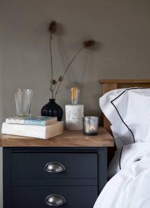 a bedside table with a night stand with books and flowers at The Barn - Georgeham North Devon in Braunton