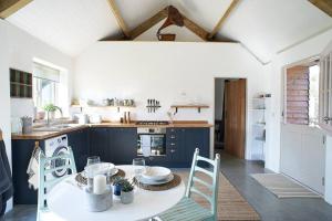 a kitchen with blue cabinets and a table and chairs at The Barn - Georgeham North Devon in Braunton