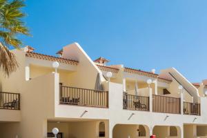 a building with balconies and a palm tree at Royal Sunset Beach Club in Adeje